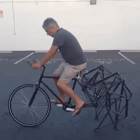 A bizarre gif of a man riding a bike with mechanical back “legs” is an example of “reinventing the wheel.”
