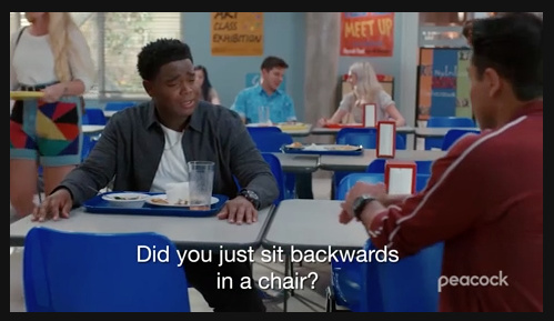 Characters from a scene in Peacock’s new “Saved By the Bell” series sit at a high school lunch table.