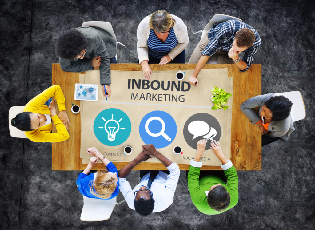 Top view of diverse employees around a conference table with graphics for inbound marketing. 
