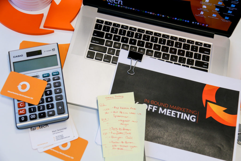 A busy office desk with a laptop, calculator, and papers discussing inbound marketing.