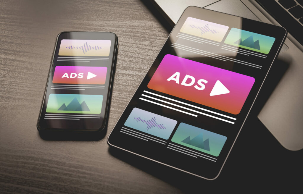 A smartphone and tablet labeled “ADS” for programmatic advertising content strategy for manufacturers.